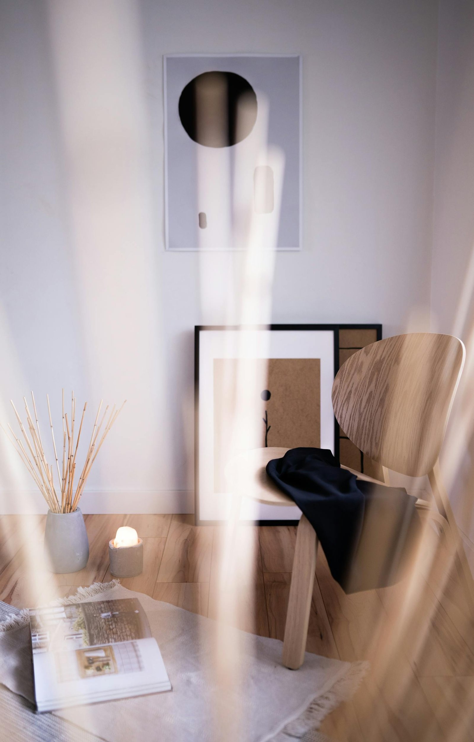 A cozy, minimalist room corner featuring a wooden chair, art, and calming accents.